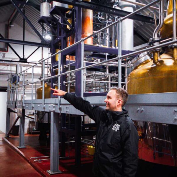 A Tour guide pointing out machinery on an Aber Falls Gin Distillery Tour
