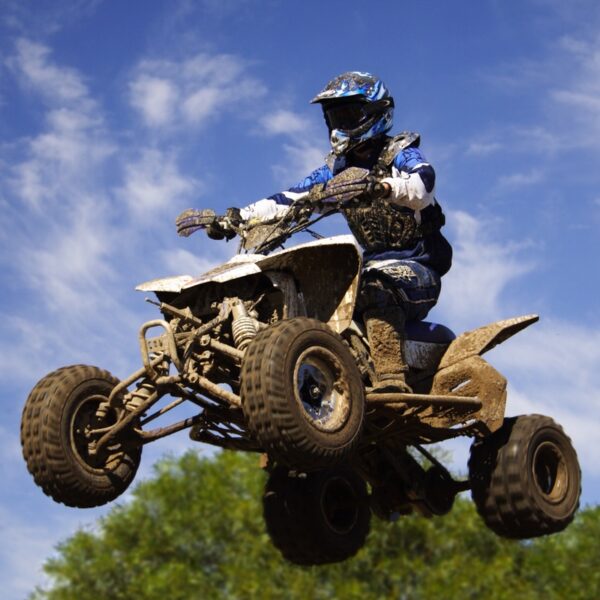 A man dressed in protective gear flying through the air on a Quad Bike during an Action To The Max Package