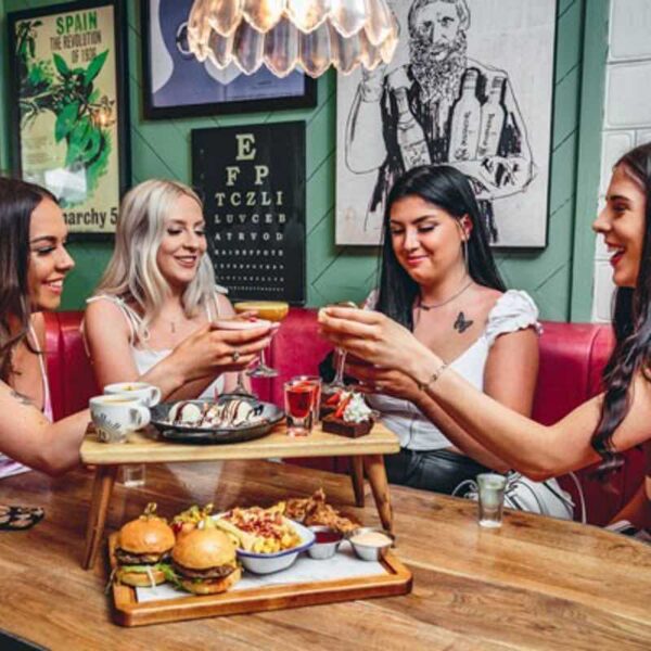 Four women sat at a booth in Revolution clinking their Afternoon Tea drinks together on a Gift Experience day