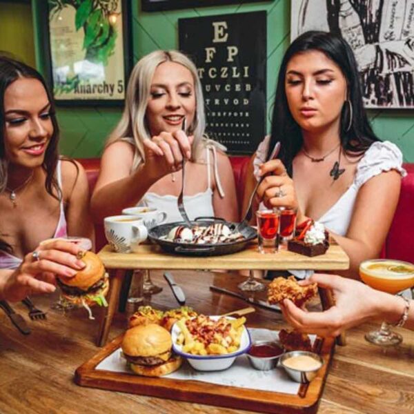 Three women sat at a table in Revolution eating their Afternoon Tea dishes