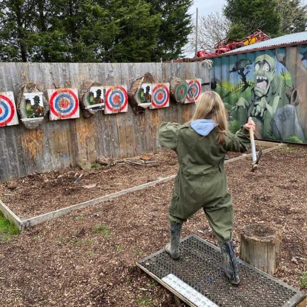 Axe throwing, lady throwing an axe dressed in a green boiler suit
