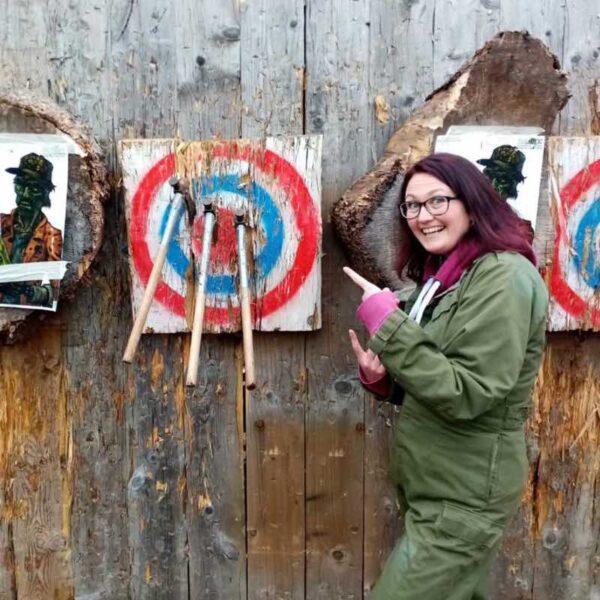 A woman pointing to a her Axe Throwing target with all bullseyes