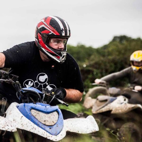 Close up of a man wearing a helmet Quad Biking through mud