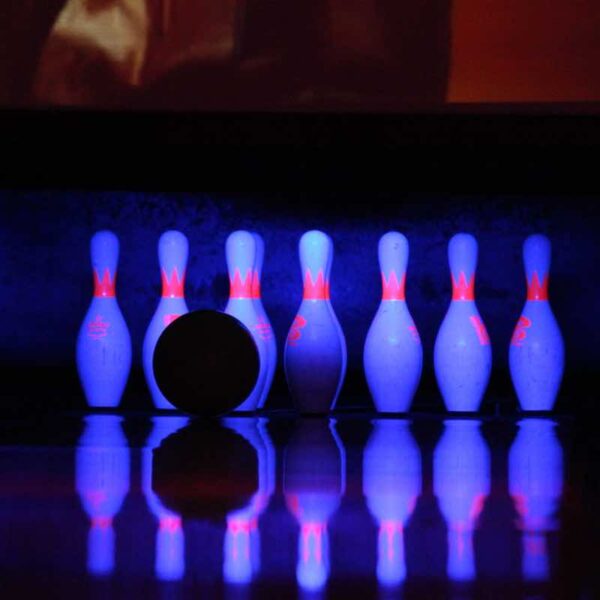 A close up of pins with a bowling ball heading towards them
