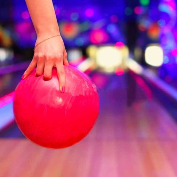 A close up of a person holding a bowling ball ready to bowl it down the lane