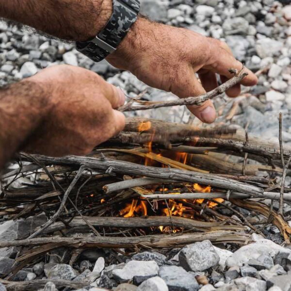 A close up of a man's hands building a fire on his Bushcraft day