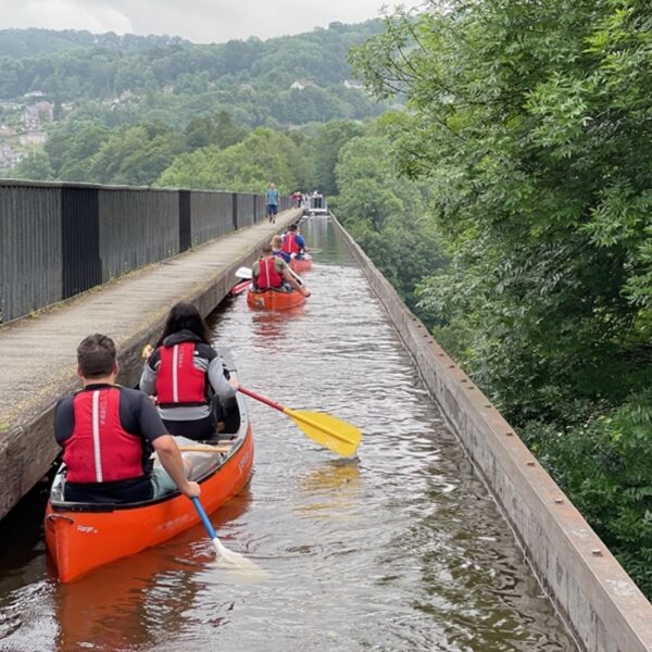 Groups Canoeing down a river wearing buoyancy aids