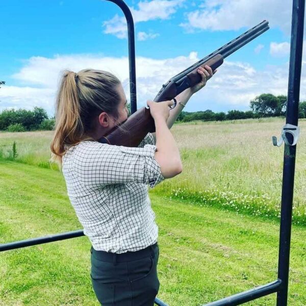 A woman Clay Pigeon Shooting aiming her shotgun toward the sky