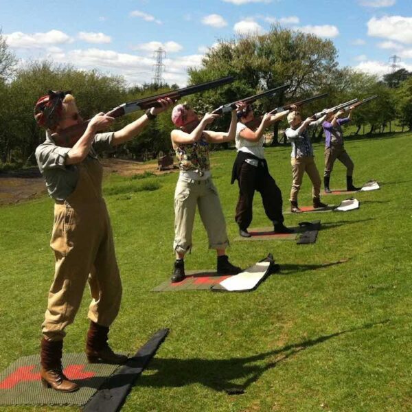 A row of ladies poised aiming their guns to the sky for Clay Pigeon Shooting