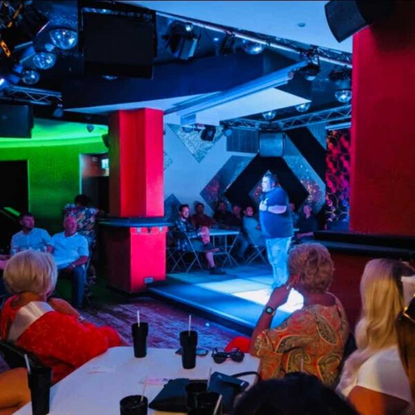 a stand up Comedian speaking to a crowd in Canvas Club