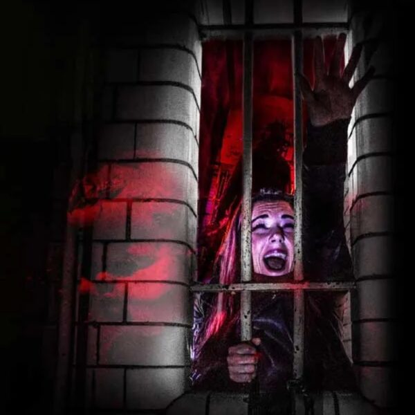 A woman screaming in a Horror Escape Room behind bars