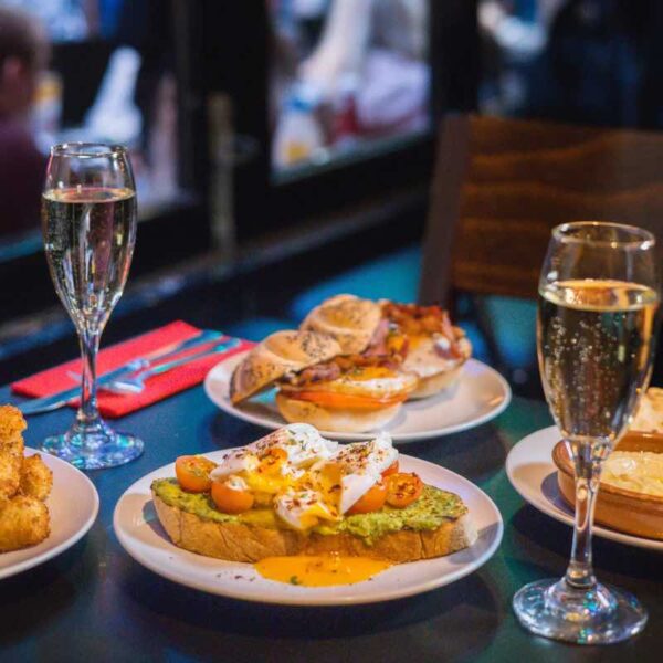 Close up of Flare Brunch dishes and 2 glasses of prosecco upon a table