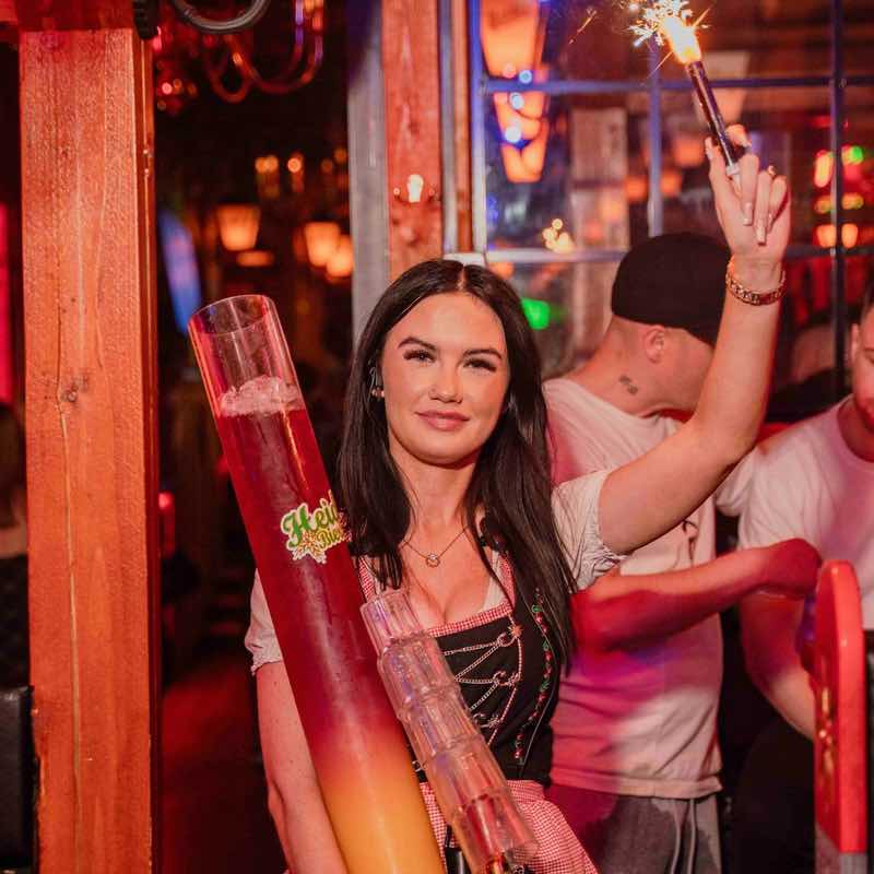 A Heidi's Bier Bar waitress carrying a Cocktail Tower to a Table with sparklers