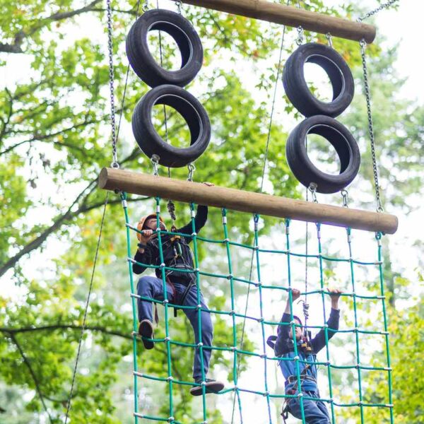 Two kids climbing up the High Ropes course
