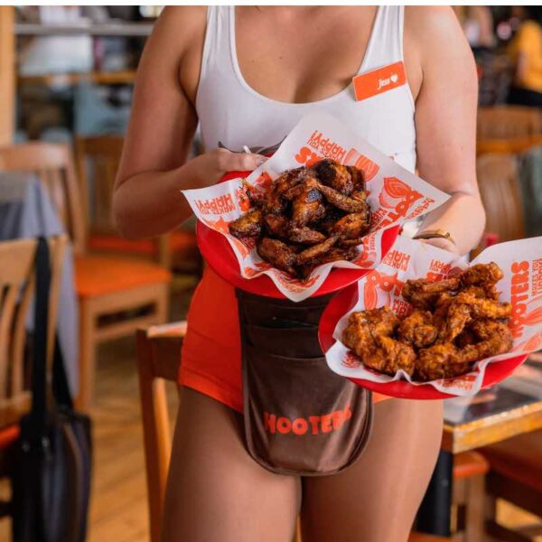 A Hooters waitress holding Party Meal chicken wings