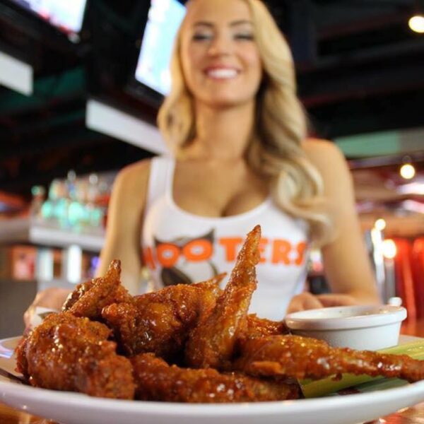 A close up Party Meal chicken wings with a Hooters waitress presenting them