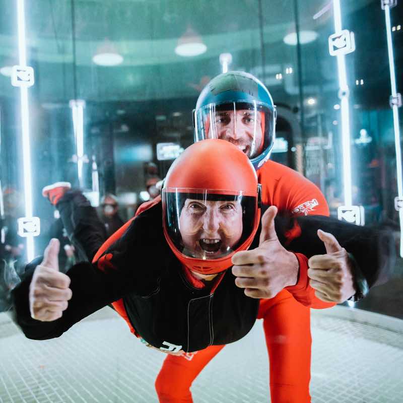 An Instructor holding a man in a simulator for his Indoor Skydiving