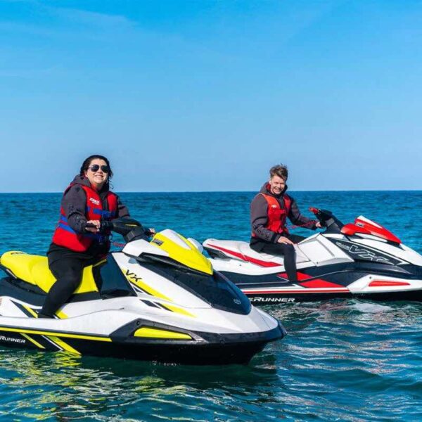 Two people riding Jet Skis in the ocean smiling