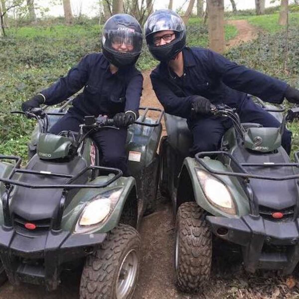 Two people wearing overalls and helmets Quad Bike Trekking through woodlands
