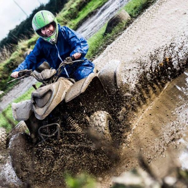 A girl dressed in protective wear Quad Biking through the mud