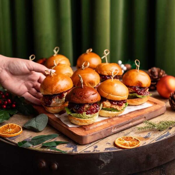 A close up of a table with Revolution Burgers and a hand reaching out to take one