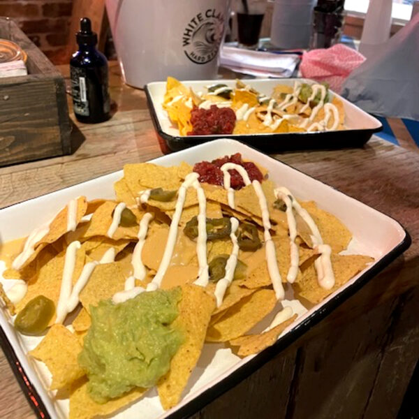 Nachos drizzled with cheese, sour cream, salsa, guacamole and scattered with sliced jalapeños.