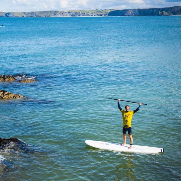 A man Stand Up Paddleboarding in the ocean while holding an oar above his head