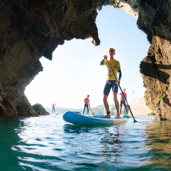 A group Stand Up Paddleboarding into a cave