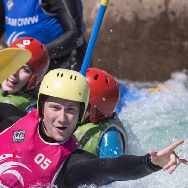 A man wearing a helmet and wetsuit enjoying White Water Rafting