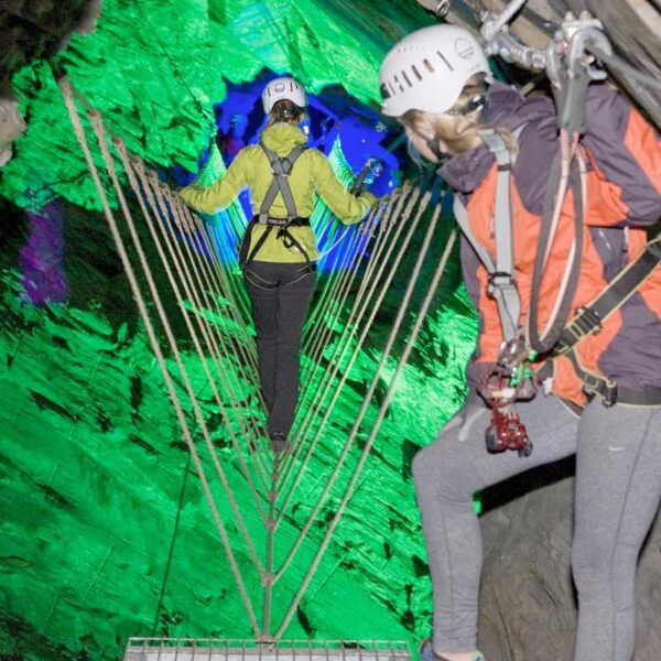 Two ladies crossing over rope in the Zip Wire Caverns