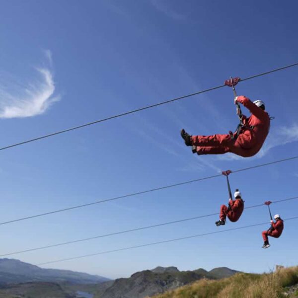3 People in red jumpsuits and helmets sliding down the Zip Wire Phoenix