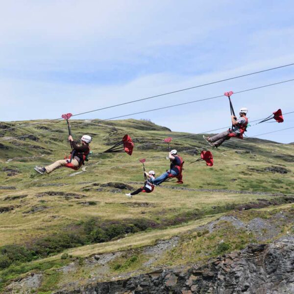 4 people flying through the sky on the Zip Wire Titan