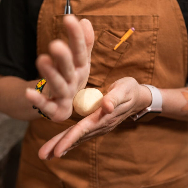A close up of a person's hands rolling a dough ball in a Baking Masterclass