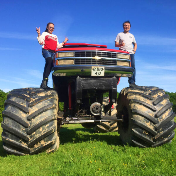 Couple posing on the wheels of a monster truck